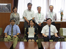 記念撮影（前列左：石田顧問，前列中央：森脇学長，前列右：田中さん）