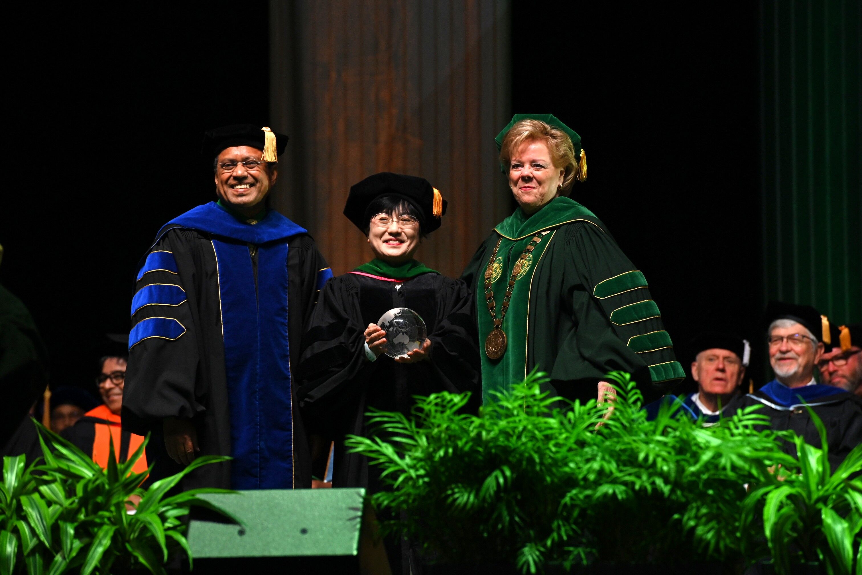 USFのレア・ロー学長（右）からトロフィーを授与される山本教授（中央）